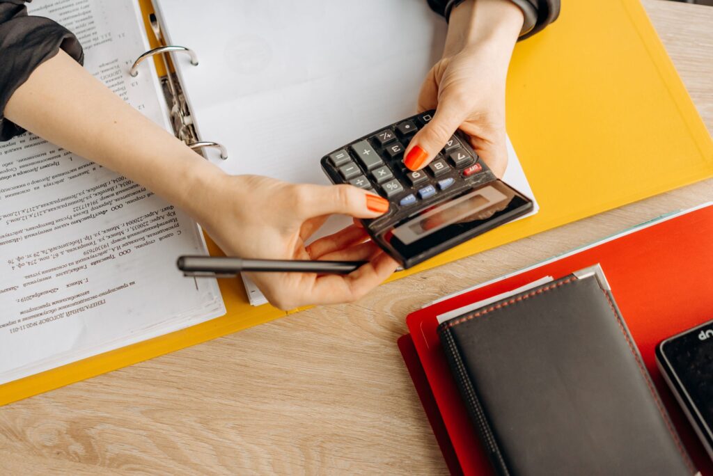 Pessoa calculando folha de pagamento com calculadora e documentos